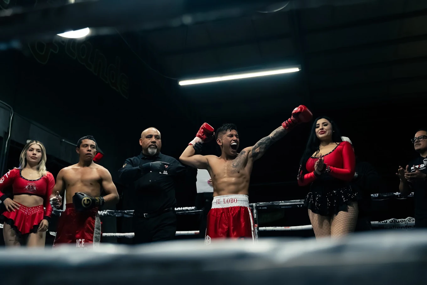 Boxer celebrating in the ring wearing the red EL LOBO trunks stitched at the shop